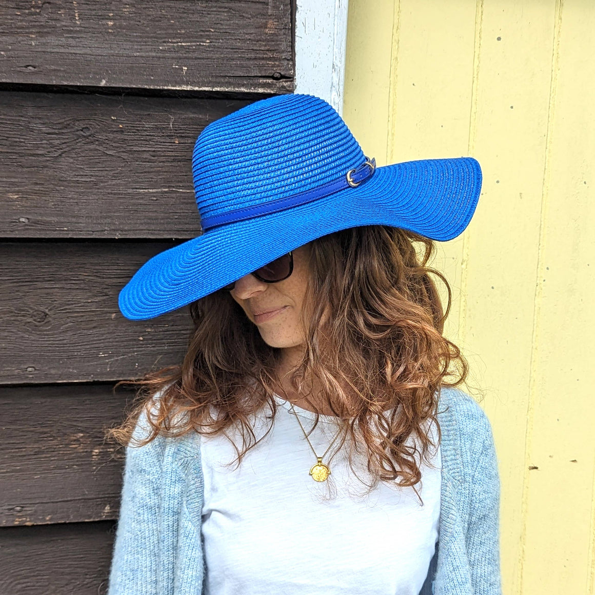 Large wide brimmed summer hat in cobalt blue on lady with long hair