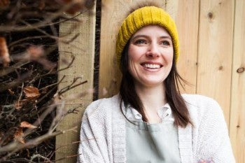 Picture of woman with hat leaning against a wall