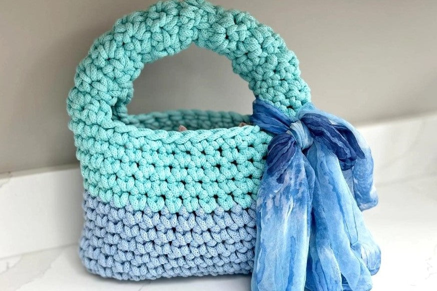 Blue hand crocheted bag with ribbon attached to handle