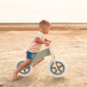 Child riding a balance bike on a sandy beach