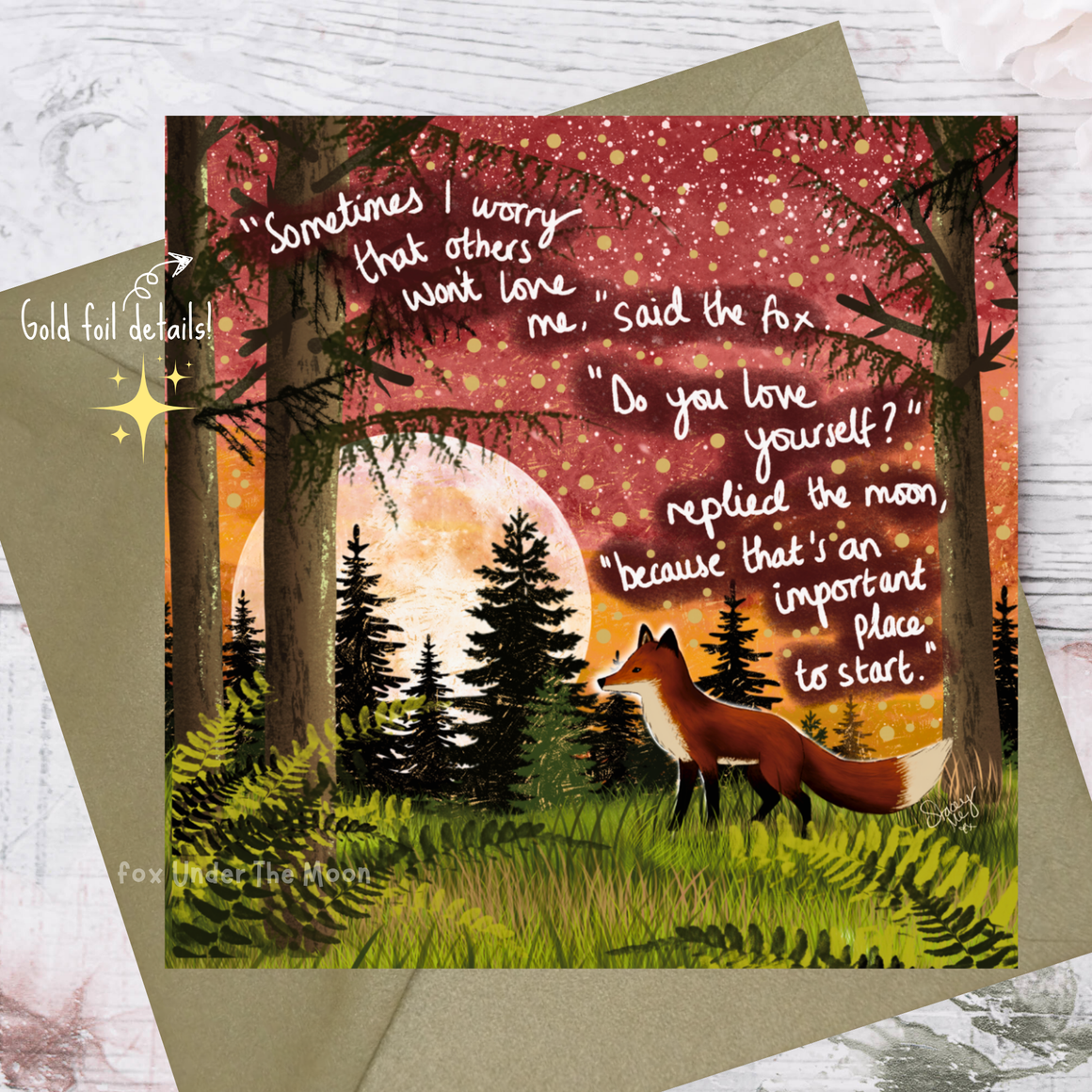 Greeting card with fox and moon illustration and inspirational quote on a wooden surface.
