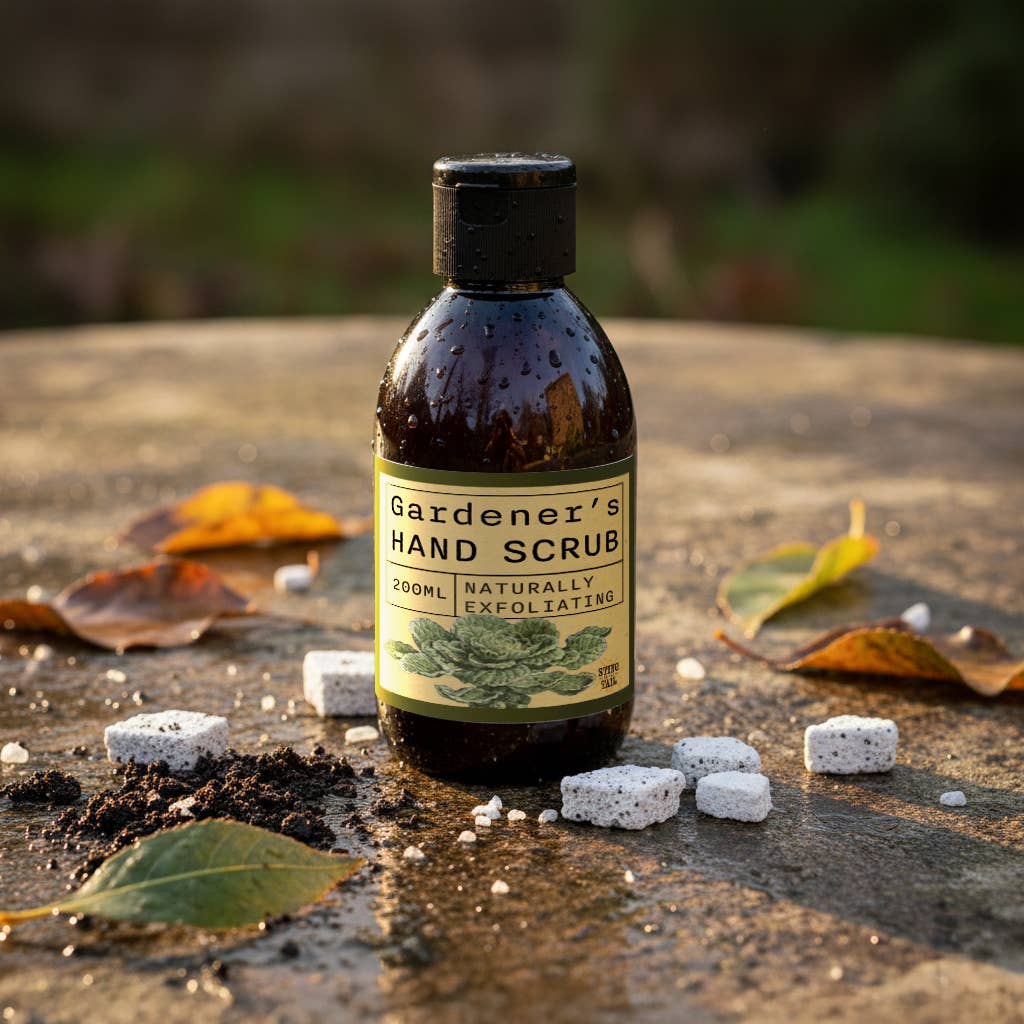 Bottle of 'Gardener's Hand Scrub' on a wooden surface with leaves and stones.