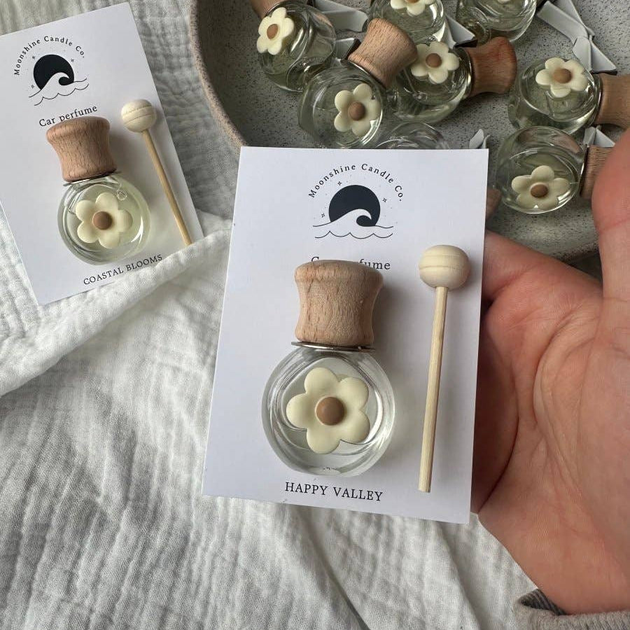 Small perfume bottles with wooden caps and flower designs on a textured surface.