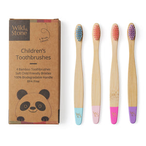 Set of four children's bamboo toothbrushes with colored bristles next to their packaging.