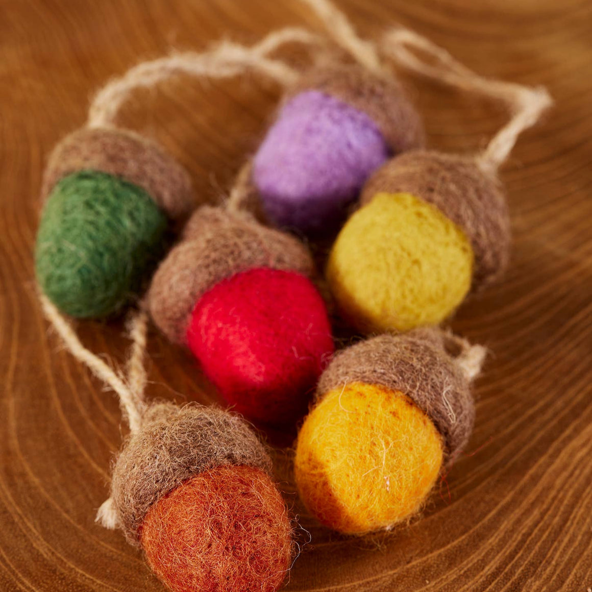 Colorful felted acorn decorations on a wooden surface