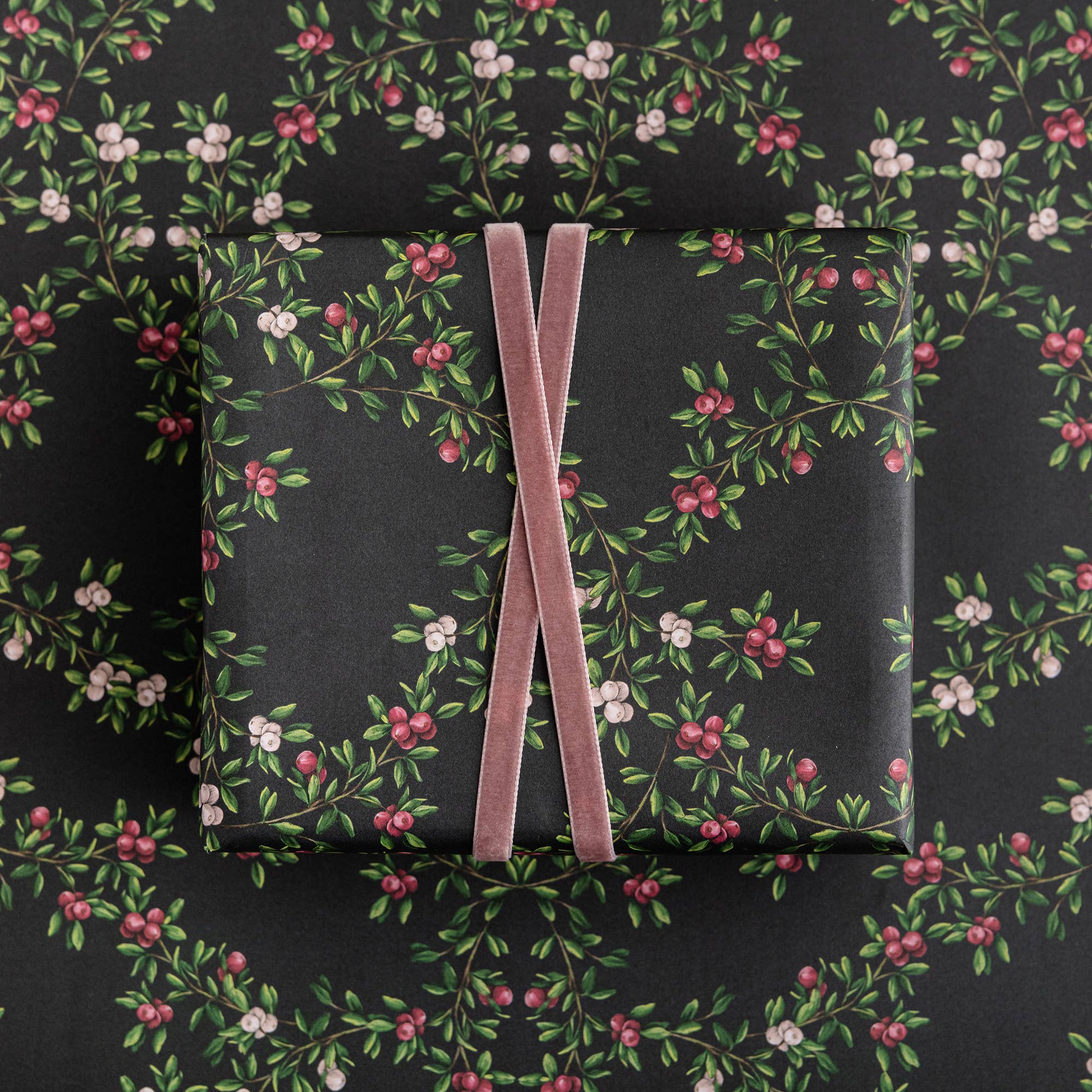 Gift box with floral pattern and pink ribbon on a matching floral background