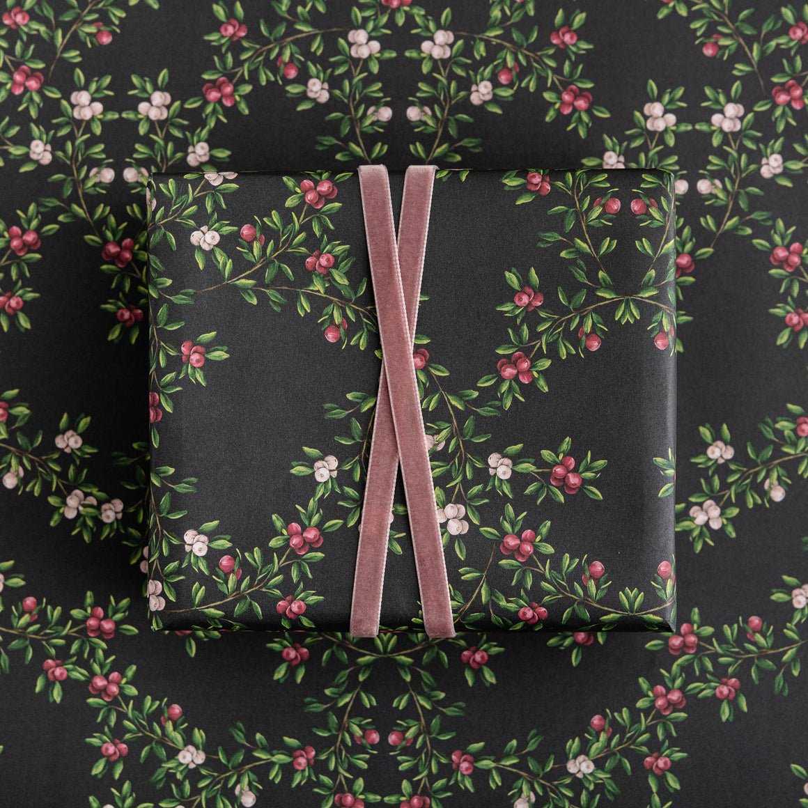 Gift box with floral pattern and pink ribbon on a matching floral background