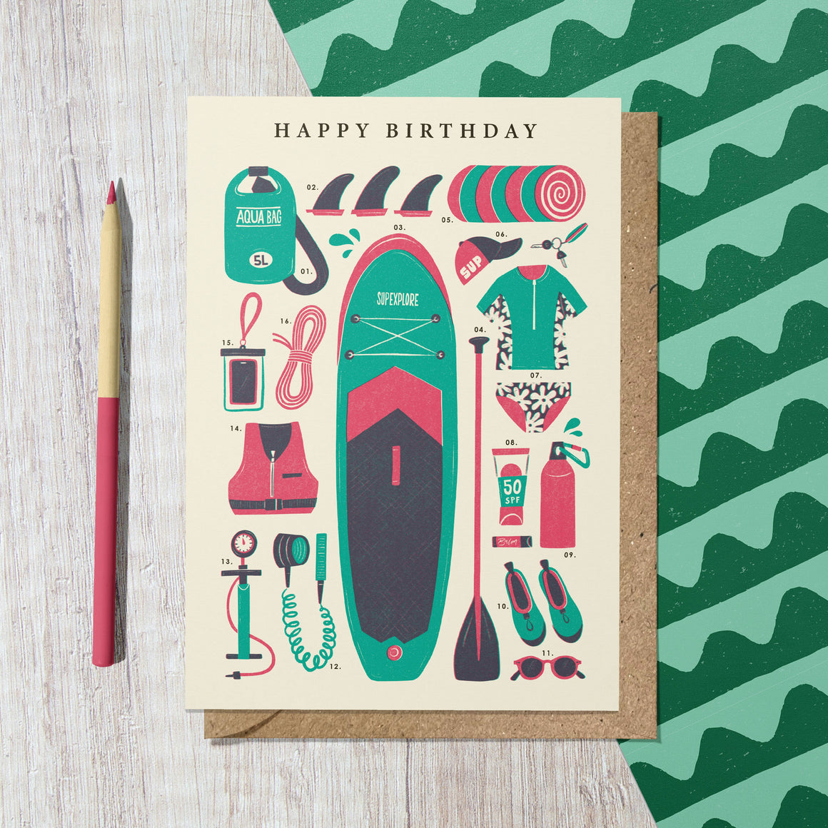 Birthday card with paddleboard illustration on a wooden surface with a green patterned background