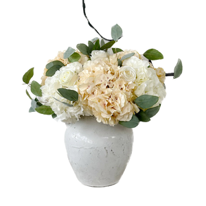 Floral arrangement with white and beige flowers in a gray vase on a white background