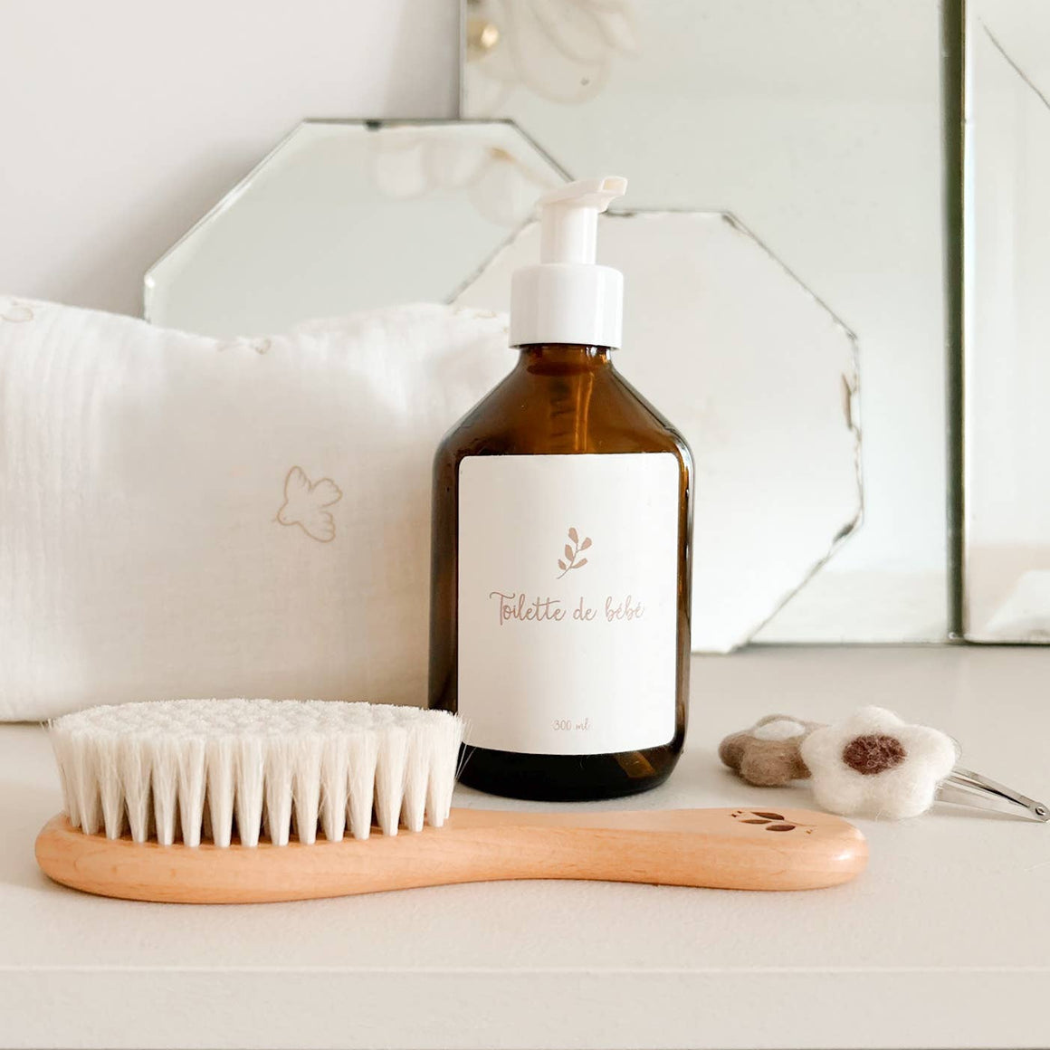 Bottle of toiletries with a brush on a white surface, mirror in the background