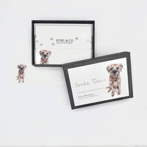 A set of notecards with an illustration of a seated border terrier on the front, accompanied by envelopes, packaged in a box.