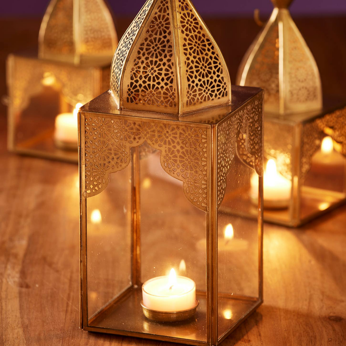 Decorative gold lanterns with candles on a wooden surface