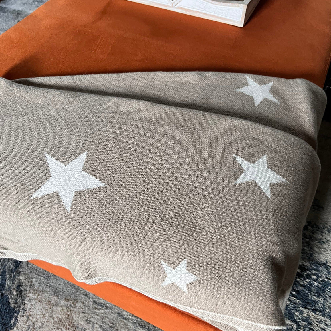 Gray blanket with white star patterns draped over a surface.