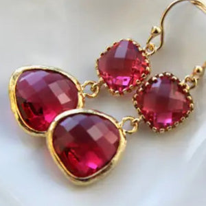Gold earrings with red gemstones on a white background