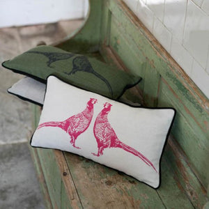 Two decorative pillows on a wooden bench with a green and white tiled wall in the background.