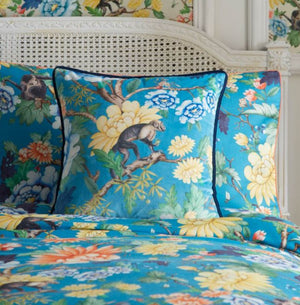 Colorful floral and monkey patterned bedding set on a bed with a floral headboard.