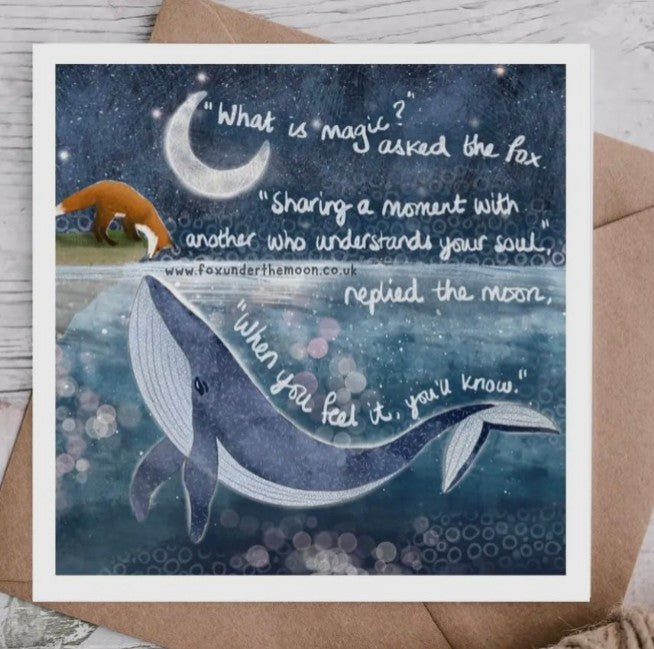 Greeting card with whale, fox, and moon illustration and quote on a wooden surface.