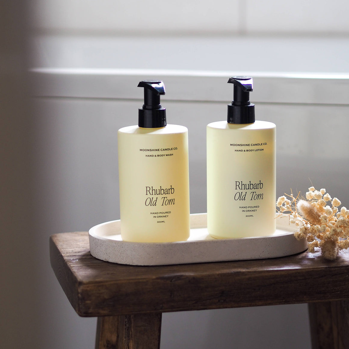 Two bottles of 'Rhubarb Old Tom' on a wooden tray with a neutral background