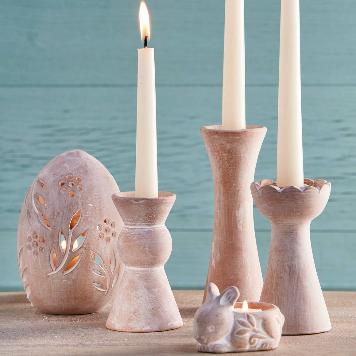 Ceramic candle holders with lit candles against a teal background