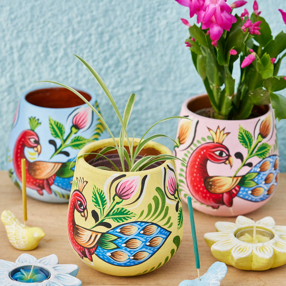 Colorful ceramic pots with floral designs on a wooden surface.