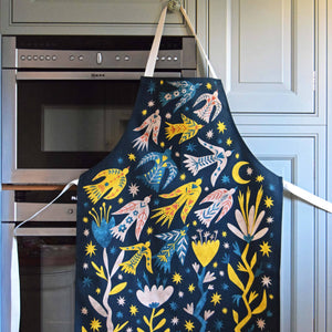 Decorative apron with colorful designs hanging on a kitchen cabinet.