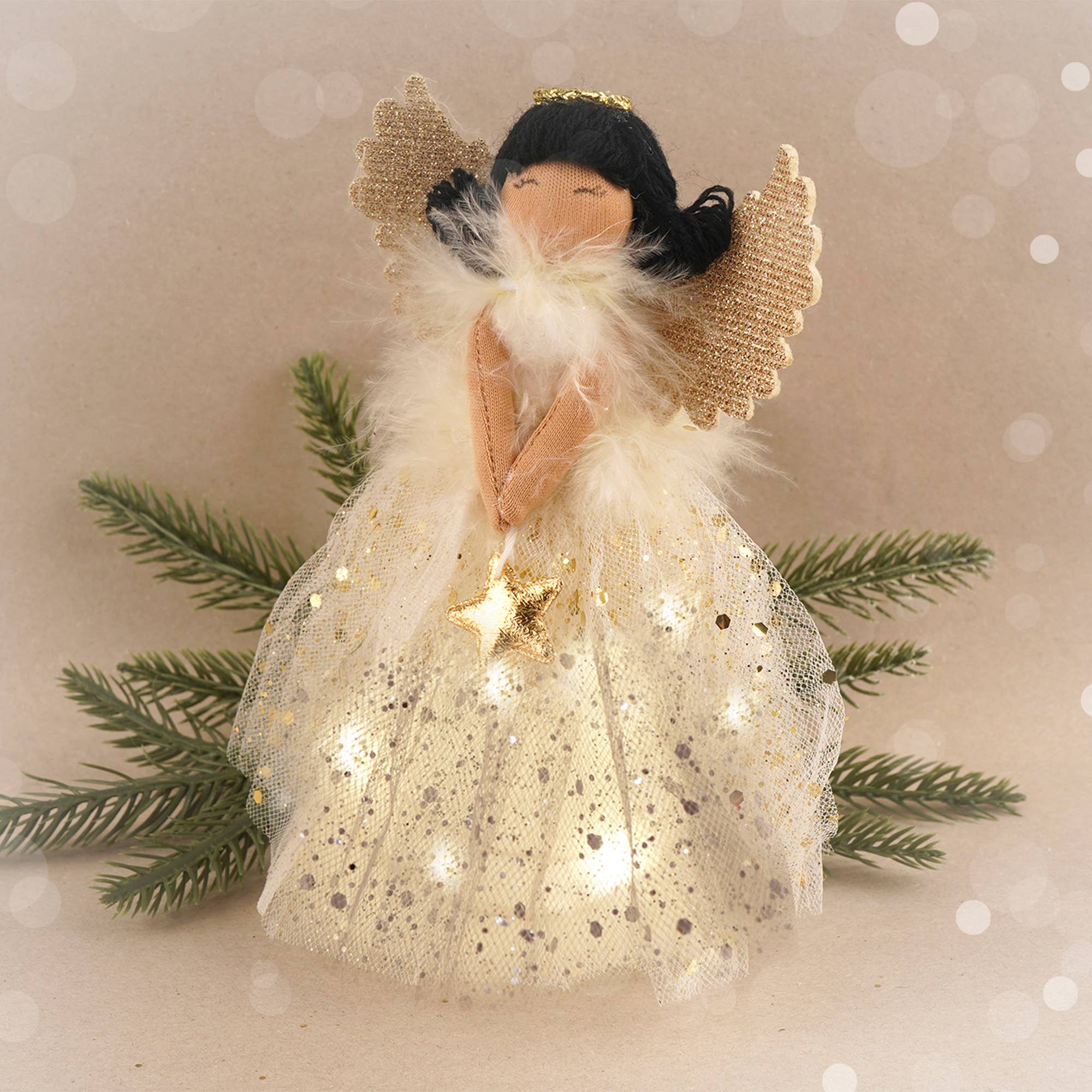 Decorative angel figurine with a star, surrounded by greenery on a soft background