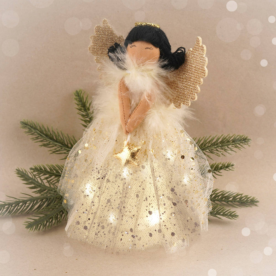 Decorative angel figurine with a star, surrounded by greenery on a soft background