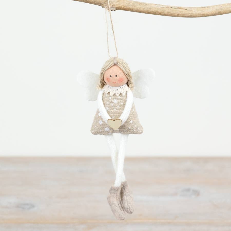 Decorative angel figurine hanging from a branch on a light wooden surface