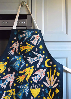 Colorful apron with abstract designs hanging on a kitchen cabinet.