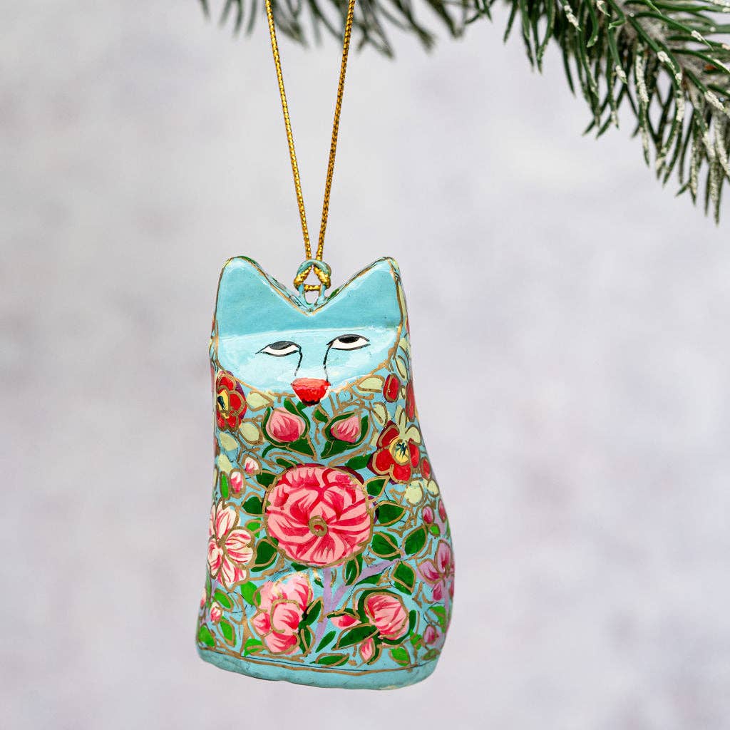 Decorative cat-shaped ornament with floral patterns hanging on a branch.