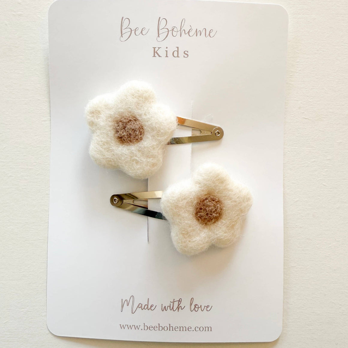 Two white flower-shaped hair clips on a 'Bee Bohème Kids' branded card.