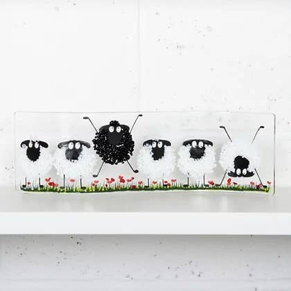 Decorative wall art with black sheep and a white background