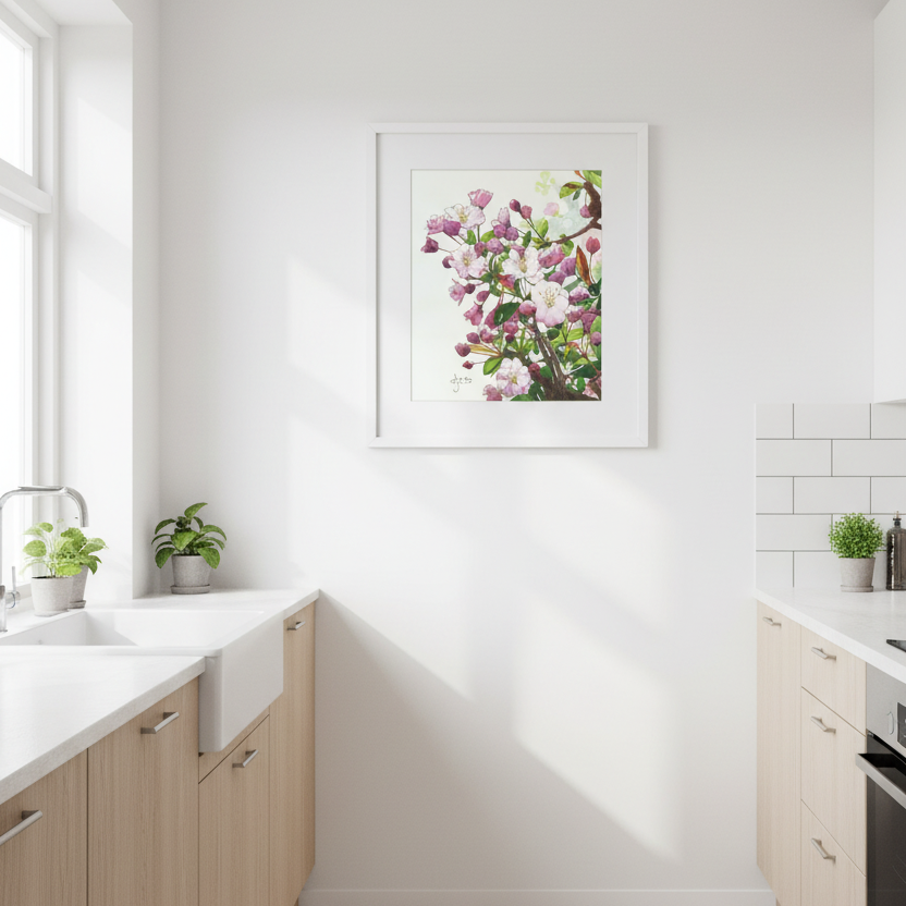 A framed floral art print featuring pink and purple flowers with green leaves, hanging on a white wall in a bright, modern kitchen with light wood cabinets and white countertops.
