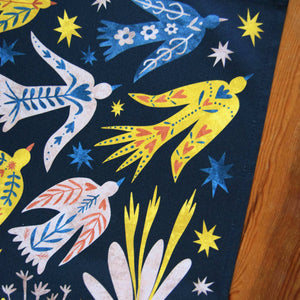 Colorful fabric with abstract designs of birds and flowers on a dark background.