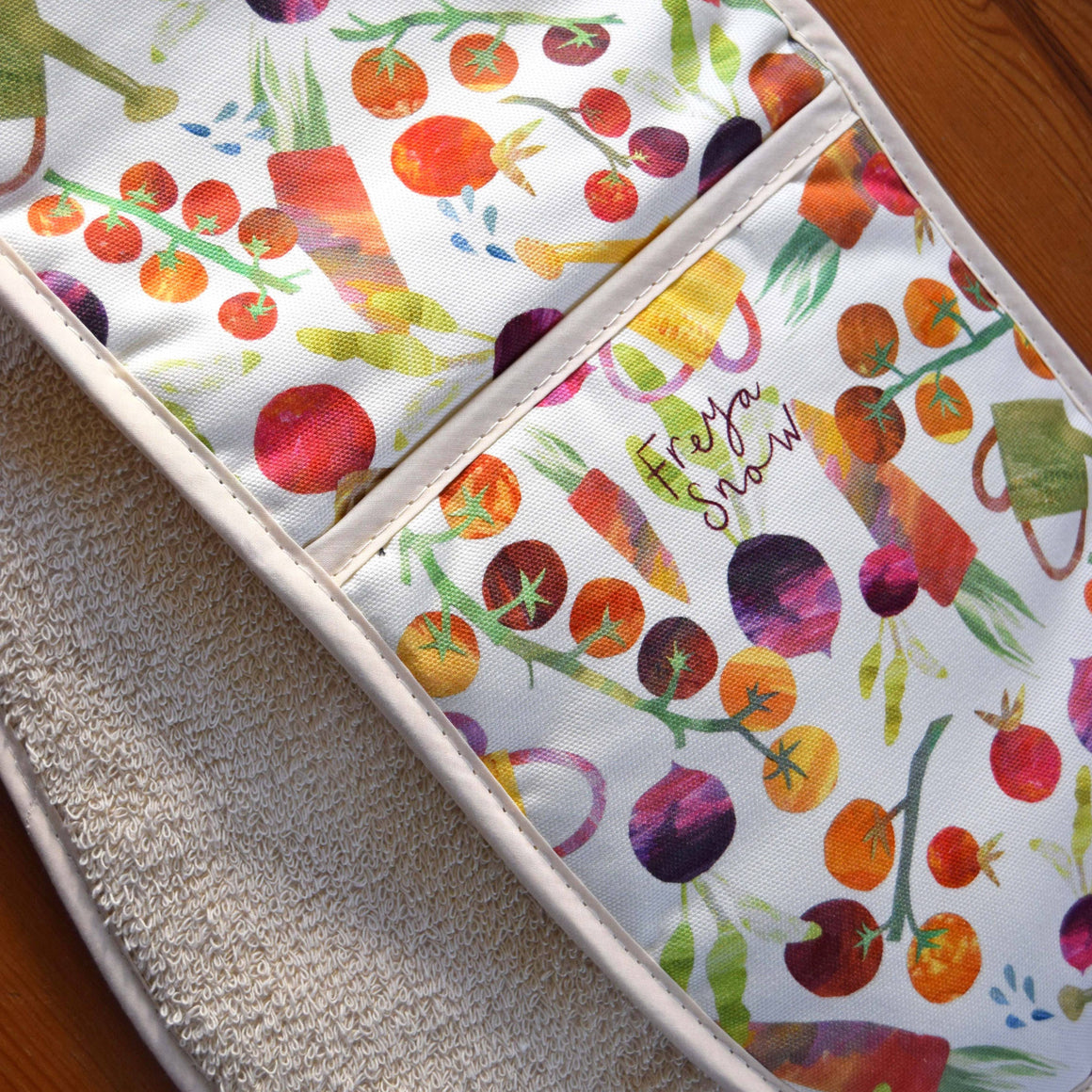 Colorful kitchen towel with vegetable pattern on a wooden surface