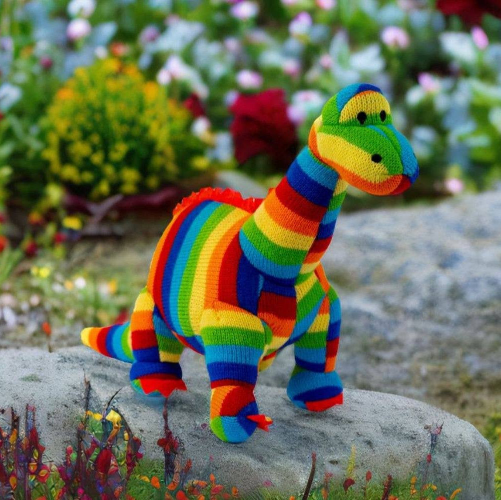 Colorful striped toy dinosaur on a rock with a garden background