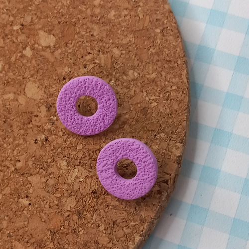 Purple circular objects on a cork board with a checkered fabric background