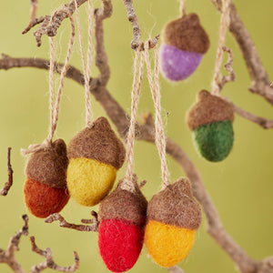 Colorful acorn-shaped ornaments hanging from a branch against a green background