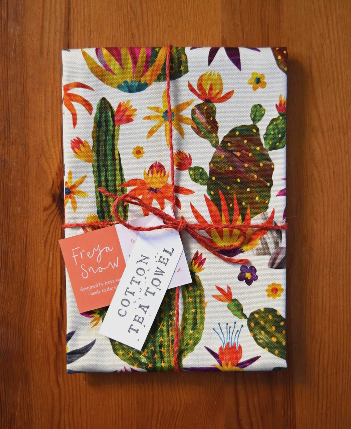 Freya Snow tea towel featuring colorful pumpkin and cactus designs on a patterned background