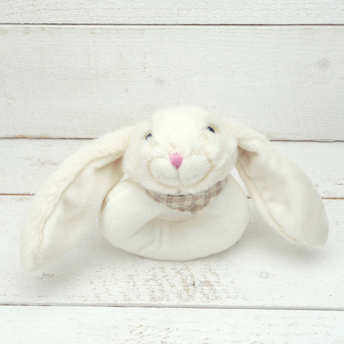 White plush bunny toy on a light wooden surface