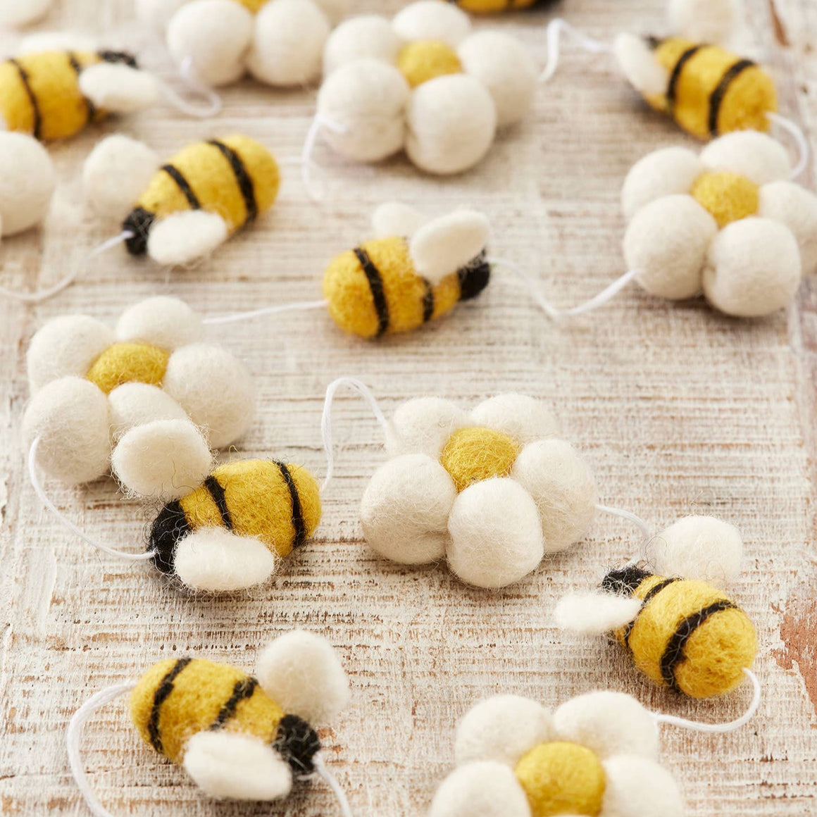 Handmade wool felt garland featuring bee and daisy motifs, crafted by Namaste as a fair trade decorative hanging.