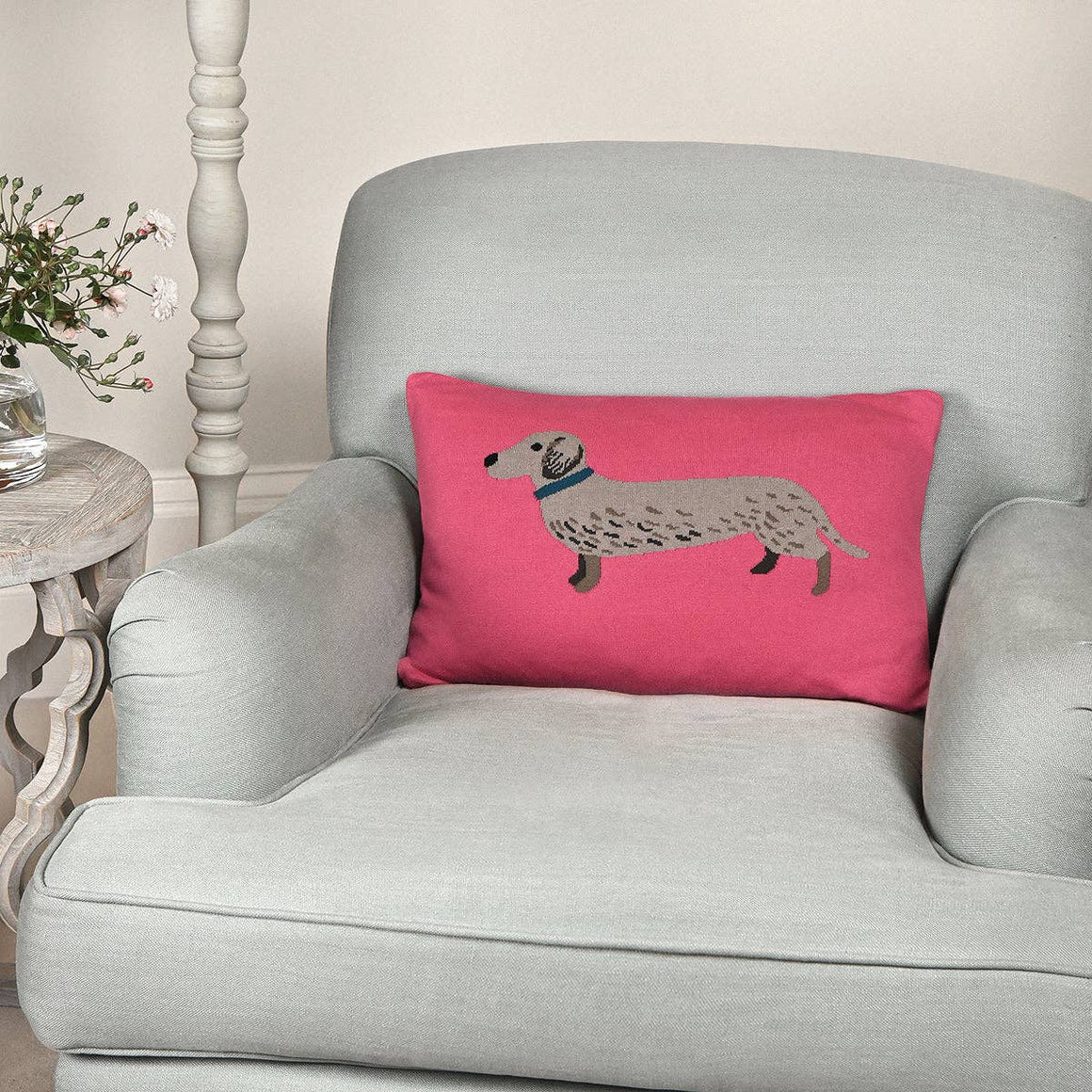Bright pink knitted cushion featuring a Dachshund design by Sophie Allport, made from soft cotton fabric.