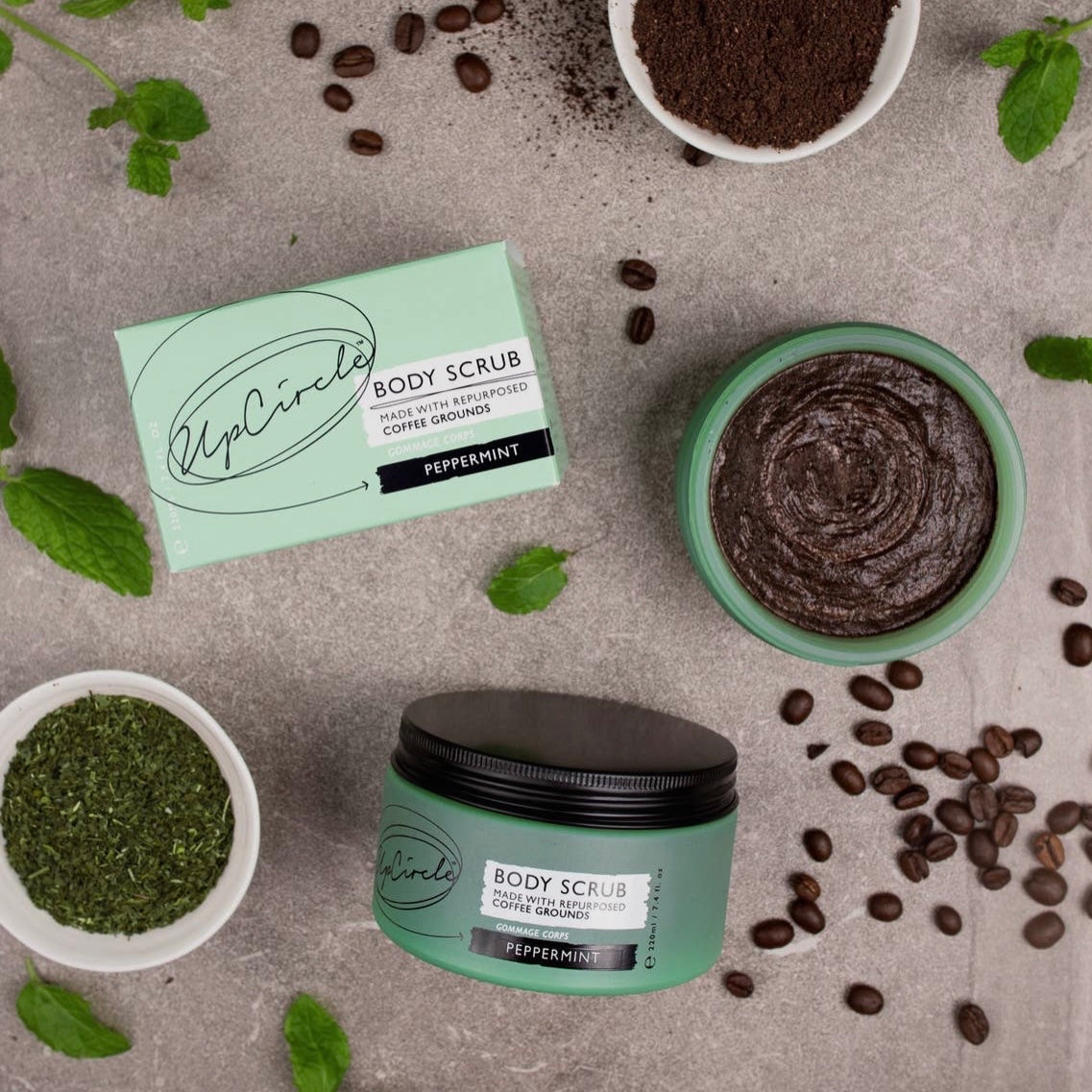 Green body scrub jar with a black lid and a natural sponge on a bathroom counter.