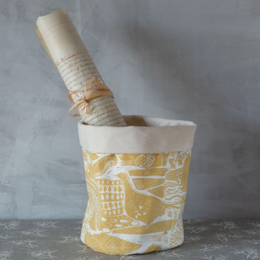 Ochre-colored pot bag by Sam Wilson featuring a woven design, perfect for carrying small plants or accessories.